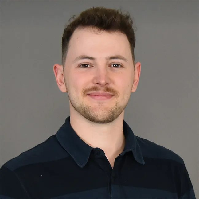 Portraitfoto von Wurster, junger Mann in schwarzem Poloshirt.